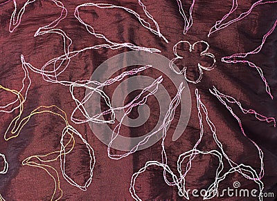 Texture of burgundy fabric with embroidered multi-colored thread flowers looks very contrasted Stock Photo
