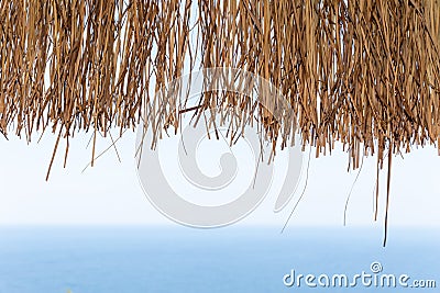 Texture of dry straw on the roof of view with a blue sea background. holiday background Stock Photo