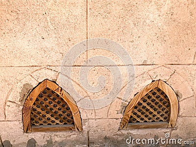 Texture of the old ancient yellow stone strong wall with windows of wooden shutters from below in the Arab Islamic Islamic warm tr Stock Photo