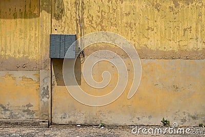 Texture of old yellow vintage wall of industrial factory with electric cable Stock Photo