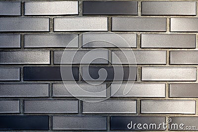 The texture of a silver wall made of ceramic facing dark gray-brown bricks. Modern decoration of cottages and houses. Stock Photo