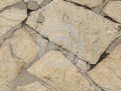 Texture of the yellow old ancient ramshackle wall with sharp carved natural natural stones, cobblestones with cemented seams and Stock Photo