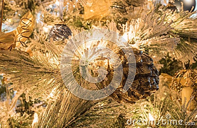 A textured gold pinecone Christmas ornament on a flocked Christmas tree Stock Photo
