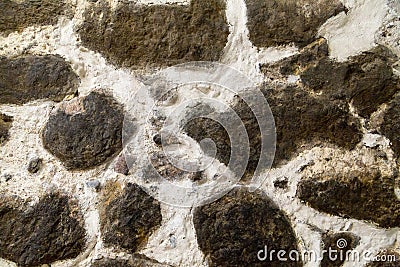 Textured stone walls built of large rough stones held together by dark lumps Stock Photo