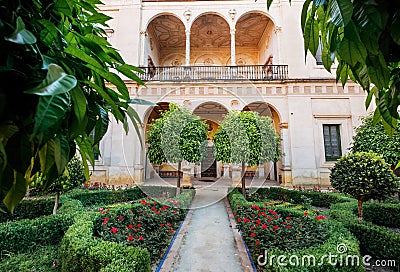 16th-century tiled gardens in the Casa de Pilatos palace with green plants and red flowers. Renaissance architecture style arches Stock Photo