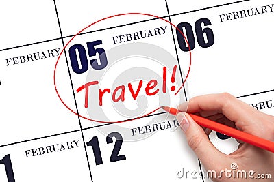 Hand drawing a red circle and writing the text TRAVEL on the calendar date 5 February. Travel planning. Stock Photo
