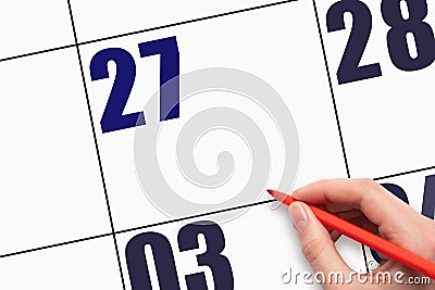 27th day of the month. Hand holding the red pen points to an empty calendar date. Stock Photo