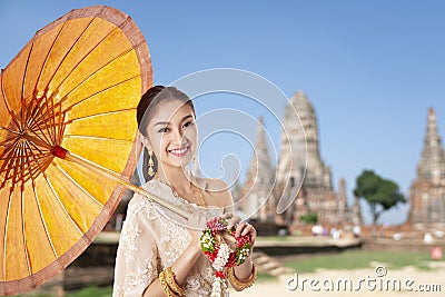 Thai asian women welcome with traditional Thai suit and umbrella on temple background Stock Photo