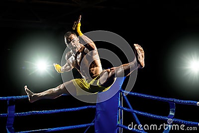 Thai boxer on boxing ring, jump and kicking Stock Photo