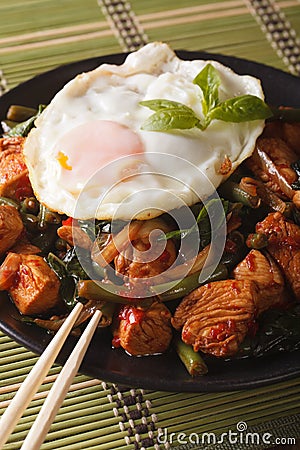 Thai chicken with basil and egg close-up on a plate vertical Stock Photo