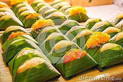 Thai Dessert: Sweet sticky rice with steamed egg custard with topping varieties wrapped with banana leaves package displayed Stock Photo