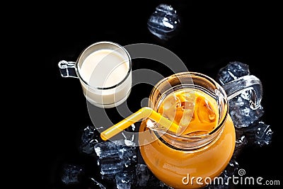 Thai ice tea in glass jar with milk and ice on black background Stock Photo