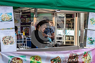 A Thai lady cooking food at a market stall for sale to the public from her stall Editorial Stock Photo