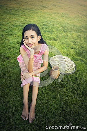 Thai local woman sitting on grass field Stock Photo