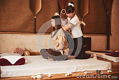 Massage therapist twisting woman arm behind her back Stock Photo