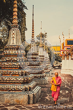 Thai monk is walking in front of old ancient pagoda at Wat Pho Temple in Bankgok, Thailand. Editorial Stock Photo
