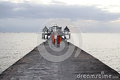 Thai monks on the bridge or Pier , which leads to the never finished and abandoned Thai temple Editorial Stock Photo