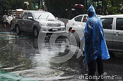 Thai officer operator volunteer staff wear rain suit working control and take care traffic road while raining strom on street at Editorial Stock Photo