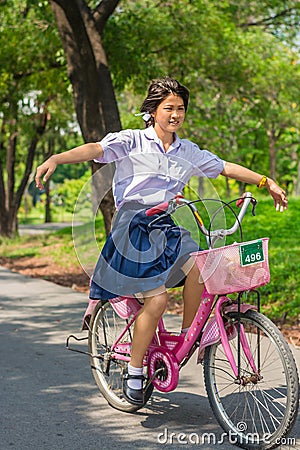 Thai Schoolgirl playing risky on a bicycle, in the park. Stock Photo