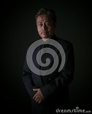 Thai senior man wearing black suit sadness emotion ,portrait by Stock Photo