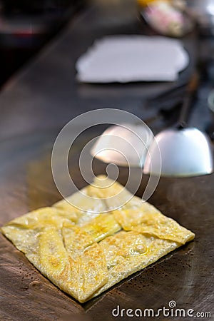 Thai street food-traditional Thai pancakes fried on a pancake close-up. with banana, chocolate, nut paste Editorial Stock Photo