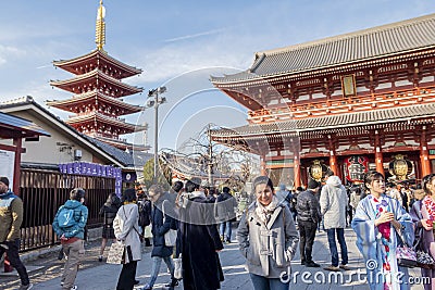 Thai woan is taking photo in front of Asakusa entrance and pagoda with a flock of Japanese people behind. Tokyo, Japan February 7 Editorial Stock Photo