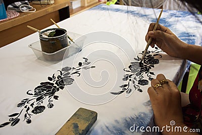 Thai woman people artist painting pattern with natural color indigo on fabric shawl scarf on table in workshop studio at house in Editorial Stock Photo
