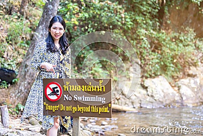 Thai women point to forbidden to swim sign in this area contradiction Stock Photo