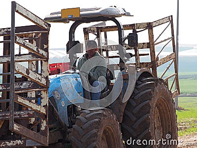 Thai worker works on an old tractor in Israeli fields Editorial Stock Photo