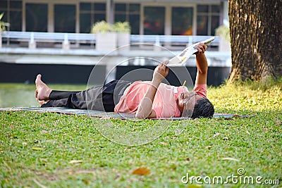 Lying on lawn in a city Park. A man reads a newspaper on the grass. The nature Editorial Stock Photo