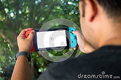 Thailand, Bangkok - October 23, 2019: Nintendo Switch, video game console for home or portable gaming. Teenager man playing game Editorial Stock Photo