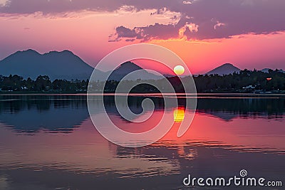 Thailands serene lake reflects vibrant hues of the setting sun Stock Photo