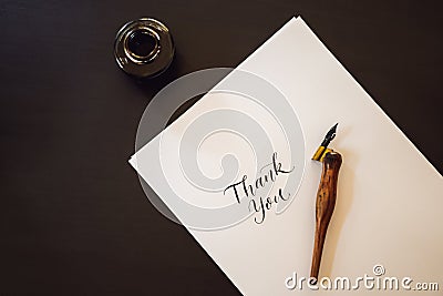 Thank you. Calligrapher Young Woman writes phrase on white paper. Inscribing ornamental decorated letters. Calligraphy Stock Photo