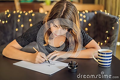 Thank you. Calligrapher Young Woman writes phrase on white paper. Inscribing ornamental decorated letters. Calligraphy Stock Photo