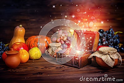 thanksgiving concept of pumpkins, apple, garlic, straw and opened chest treasure with mystical miracle light on wooden Stock Photo