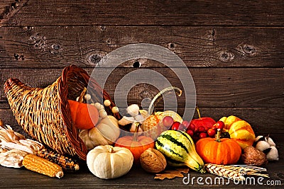 Thanksgiving cornucopia filled with autumn pumpkins and vegetables against dark wood Stock Photo