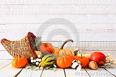 Thanksgiving cornucopia filled with autumn vegetables and pumpkins against white wood Stock Photo