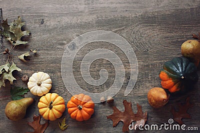 Thanksgiving season still life with colorful small pumpkins, acorn squash, fruit and fall leaves over rustic wood background Stock Photo