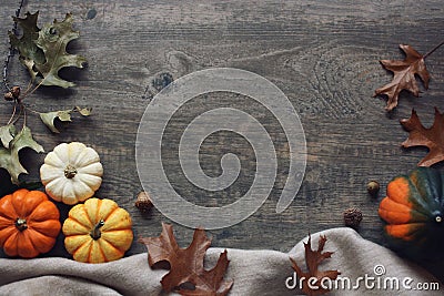 Thanksgiving season still life with colorful small pumpkins, acorn squash, soft blanket and fall leaves over rustic wood backgroun Stock Photo