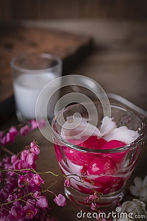 Thapthim krop, mock pomegranate seeds in coconut and syrup in the glass on the wood table there are flower, spoon and coconut milk Stock Photo