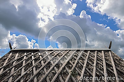 Thatch roof and rainy clouds and sun behind clouds Stock Photo