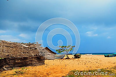 Thatched coconut leaf house or fishing hut and boats on tropical beach Stock Photo