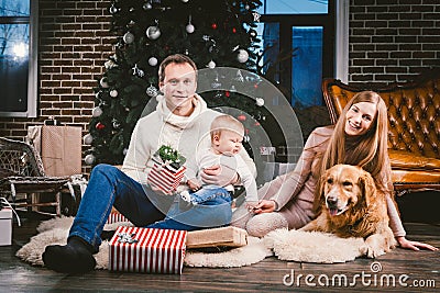 Theme Christmas and New Year family circle and domestic pet. Mom dad and child 1 year old Caucasian woman sitting on Stock Photo