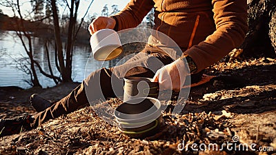 The theme of tourism is hiking and traveling in nature. Hands A Caucasian man uses equipping to cook food outside. A Stock Photo
