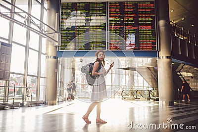 Theme travel and tranosport. Beautiful young caucasian woman in dress and backpack standing inside train station or terminal looki Stock Photo