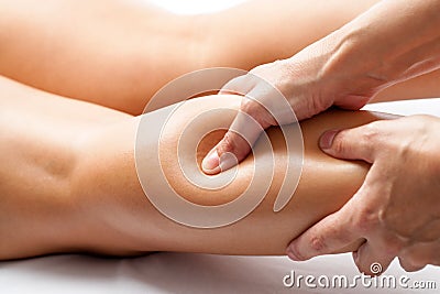 Therapist applying pressure with thumb on female calf muscle. Stock Photo