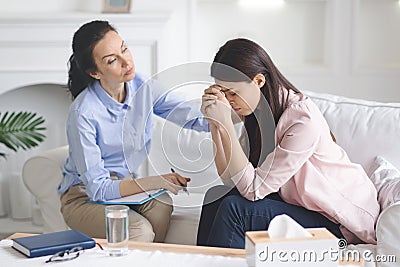 Therapist comforting her depressed crying woman patient Stock Photo