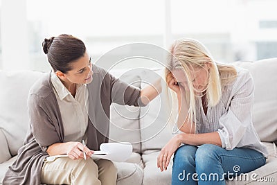 Therapist comforting upset woman on sofa Stock Photo
