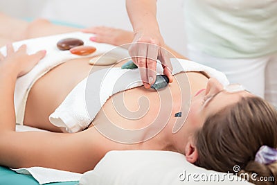 Therapist placing stones on woman`s body Stock Photo