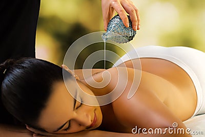 Therapist pouring massage oil on woman`s back. Stock Photo